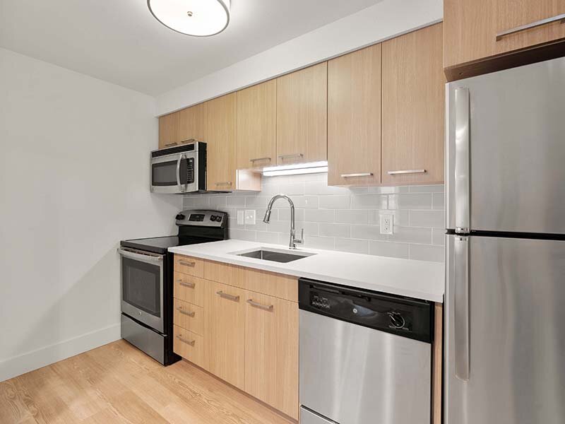 Apartment Kitchen with Wood Style Cabinets and Flooring | Avia Lofts on Parkway