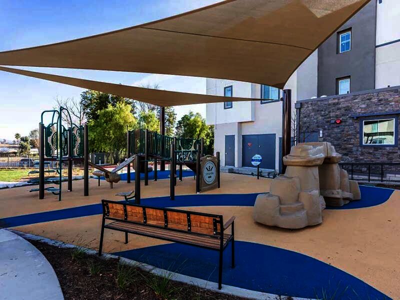 Outdoor Playground with Bench and View of Apartment Complex | Monamos Terrace