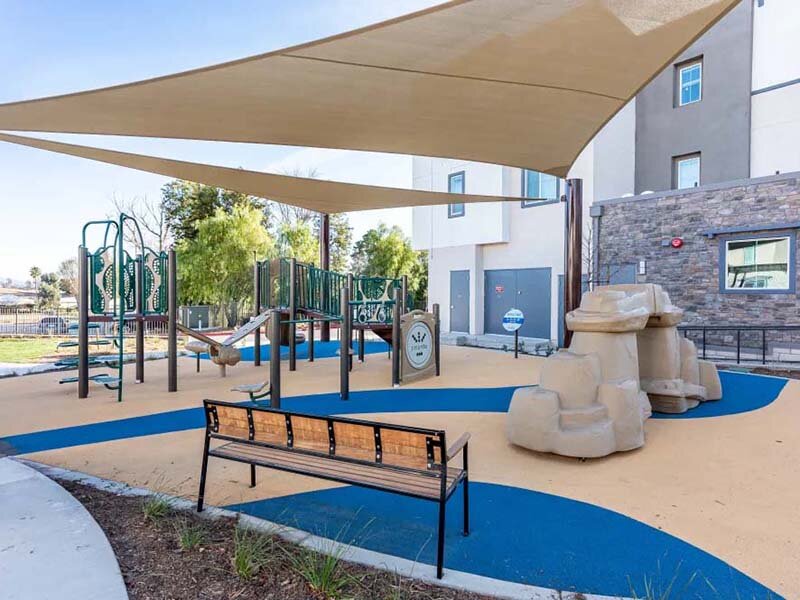 Outdoor Playground with Bench and View of Apartment Complex | Monamos Terrace
