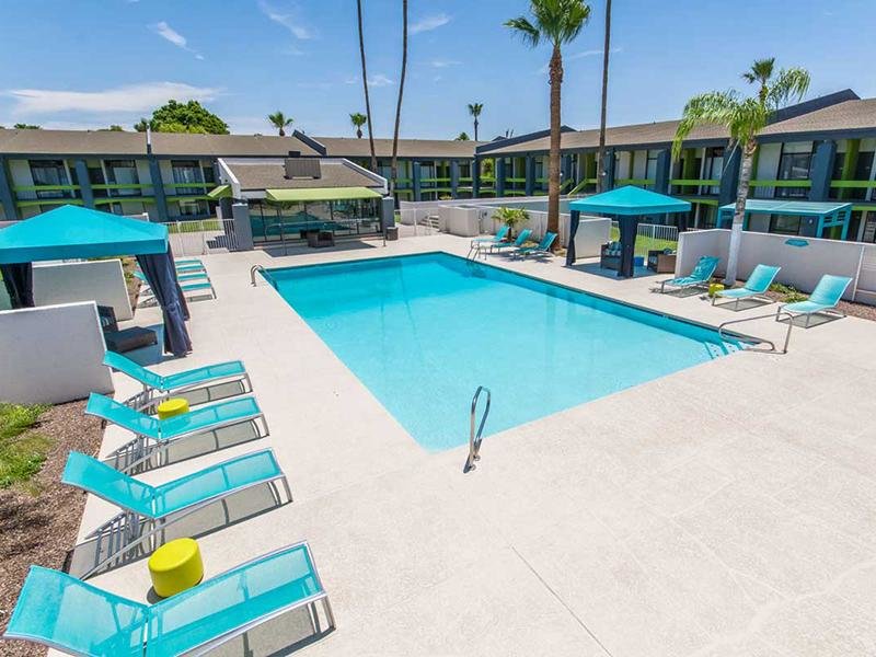 Pet Friendly Apartments in Phoenix AZ - Portola Biltmore - Sparkling Pool with Lounge Seating, Umbrellas, and Greenery