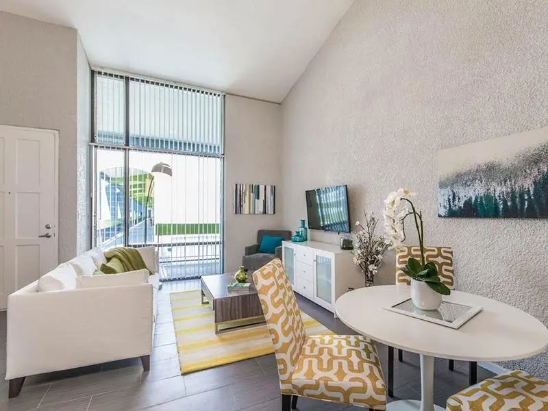 Camelback East Village Apartments - Portola Biltmore - Well Lit Living Room with Attached Dining Area, Floor to Ceiling Windows, and Furniture