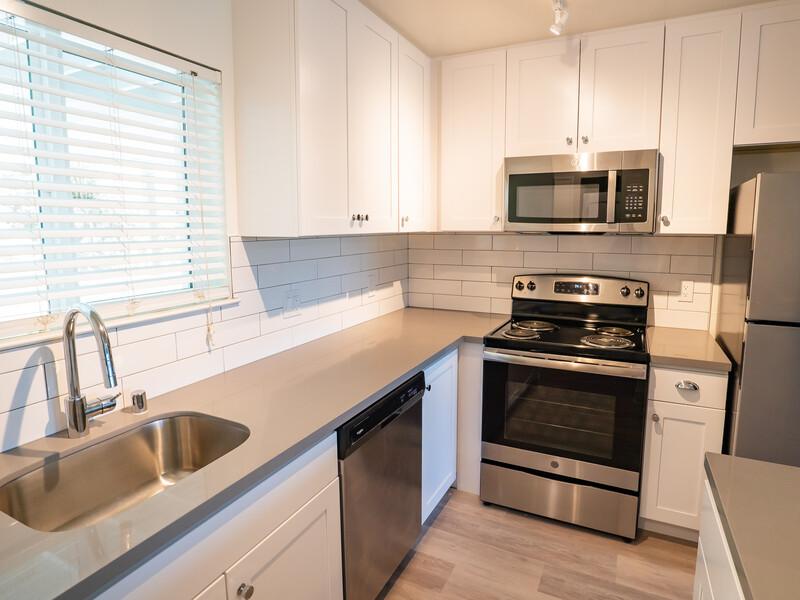 Apartments in San Rafael CA for Rent - McInnis Park - Kitchen with Grey Countertops, White Cabinets, Stainless Steel Appliances, and a Window.