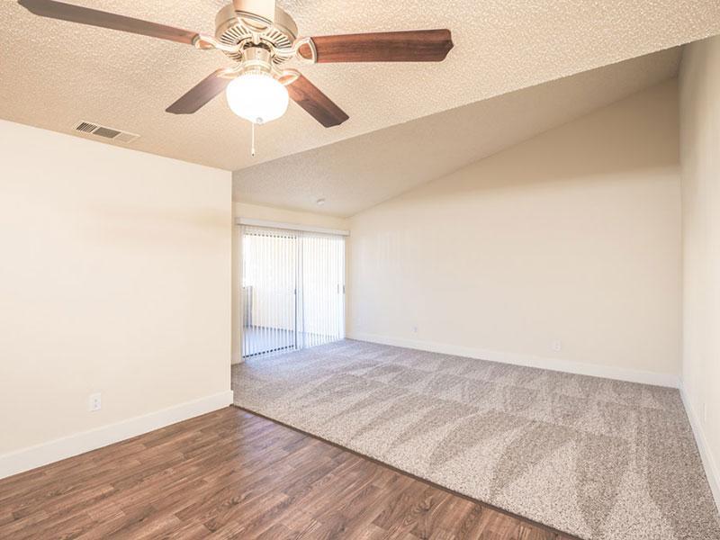 Apartments in Upland for Rent - Parc Claremont - Open-Concept Living Area with Grey Carpeting, Sliding Glass Patio Doors, and Ceiling Fan