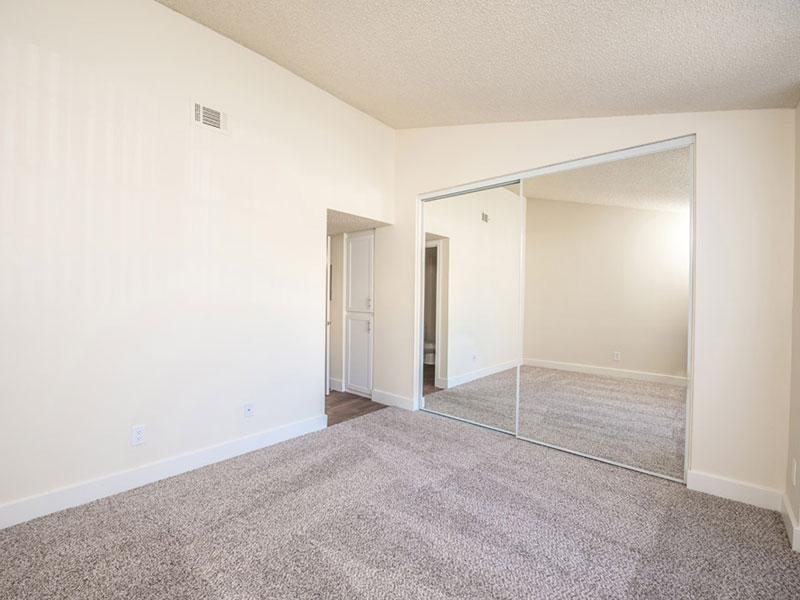 Upland Apartments for Rent - Parc Claremont - Spacious Bedroom with Grey Carpeting, Beige Walls, and Mirrored Closet Doors