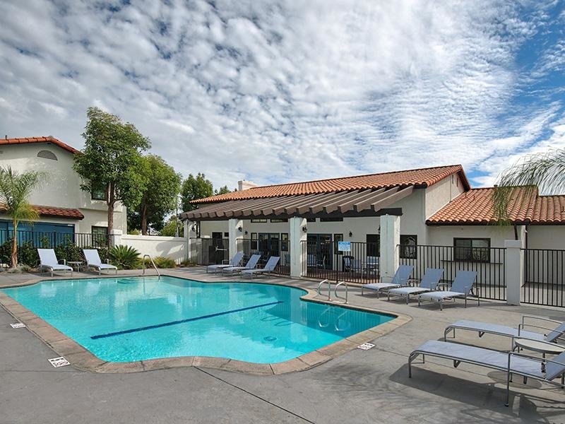 Apartments for Rent in Santa Fe Springs - Costa Azul Senior - Outdoor Pool Area Next To Community Clubhouse with Lounge Chairs Surrounded by Greenery
