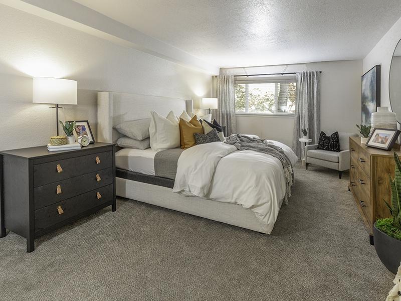 One-Bedroom Apartments in Salt Lake City, UT - Foothill Place - Bedroom with Plush Comforter, Grey Dresser, and Corner Reading Chair