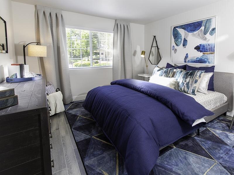 Three Bedroom Apartments in Taylorsville, UT - Spacious Bedroom with Wood-Style Flooring and Large Window