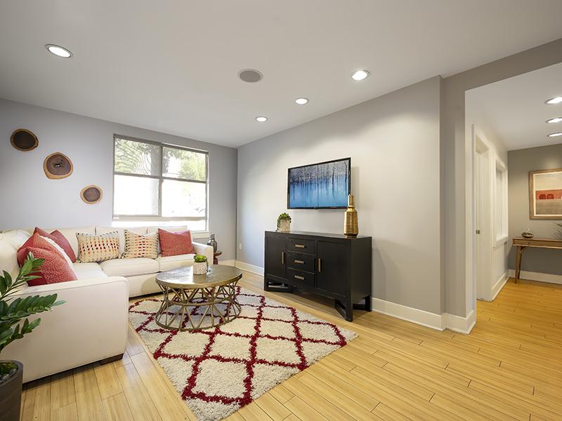 Two-Bedroom Apartments in Studio City CA - The Thomas Apartments - White Sectional Couch, Large Window, Ceiling Mounted Lighting, and White and Red Ar