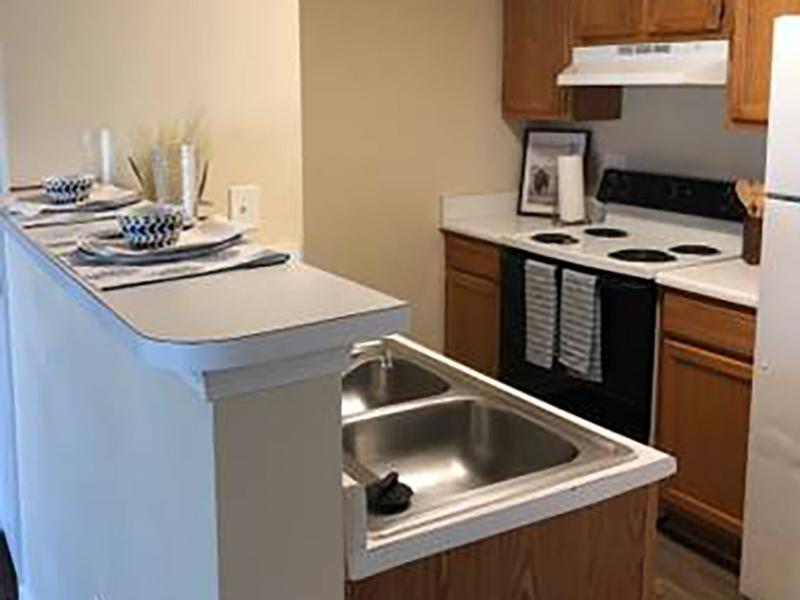 Model kitchen with breakfast bar has modern appliances and wood-style flooring at Bridgewater at Town Center Apartments.