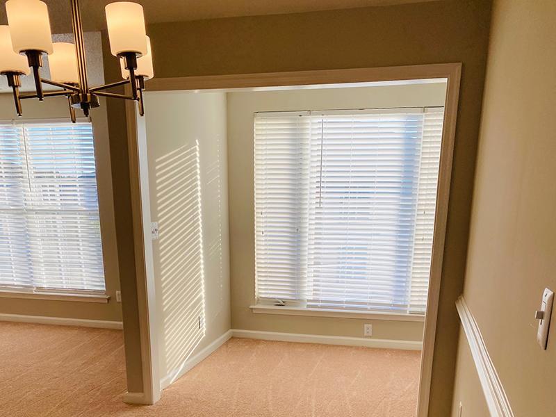 Large windows with blinds in a carpeted room at The Lakes at Town Center Apartments in Hampton.