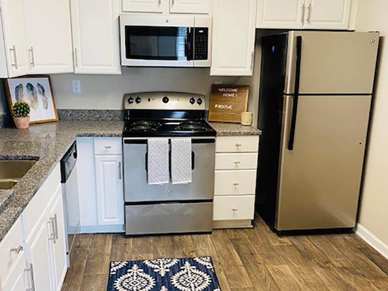 Model kitchen with stainless steel appliances and wood-style flooring at The Lakes at Town Center Apartments