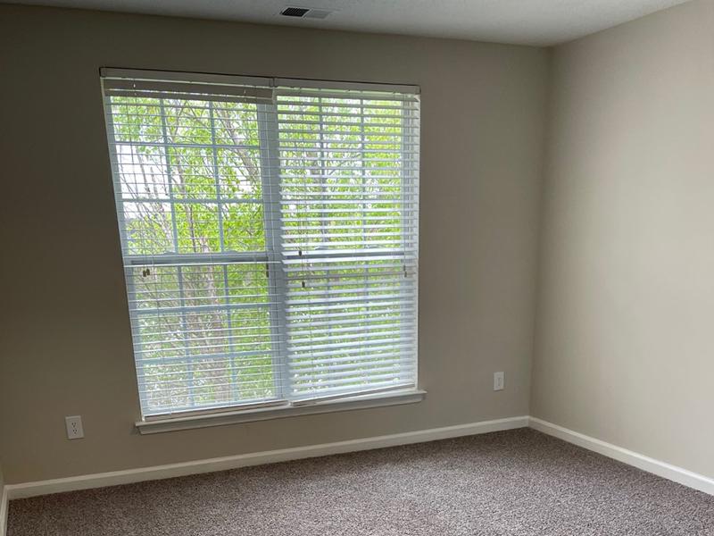 A bedroom with carpet and a large window at The Lakes at Town Center Apartments in Hampton.