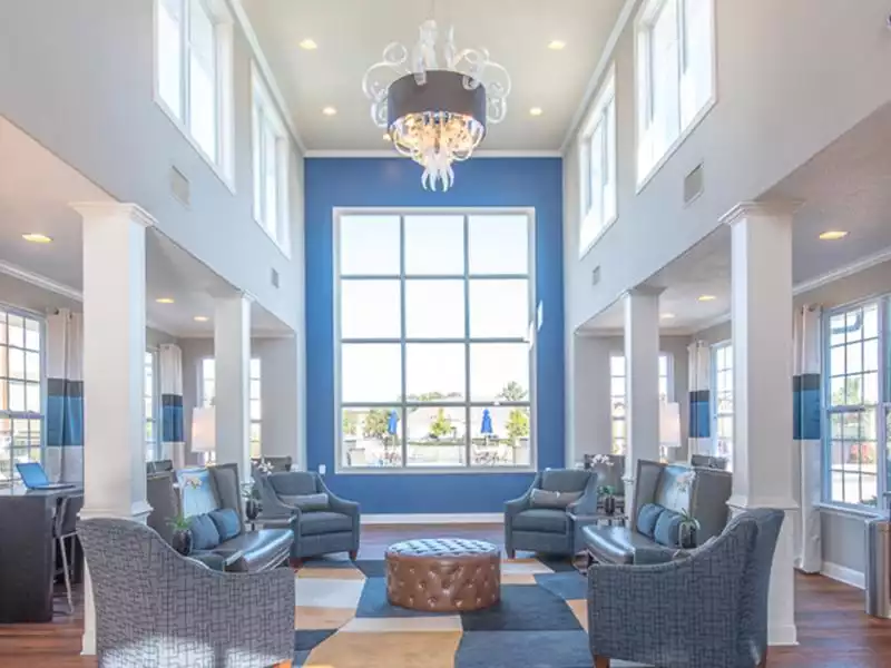 The resident lounge is decorated with upholstered chairs and couches at The Lakes at Town Center Apartments.
