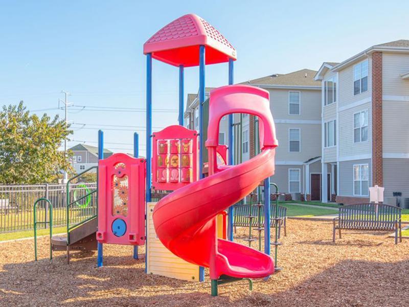 A large slide and climbing equipment sit in the playground at The Lakes at Town Center Apartments.