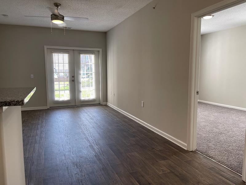 The living room leads to a carpeted bedroom in an apartment at The Lakes at Town Center.