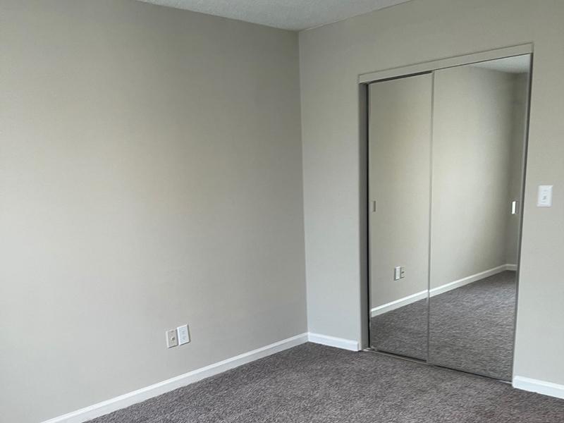 A bedroom with a mirrored closet at The Lakes at Town Center Apartments in Hampton.
