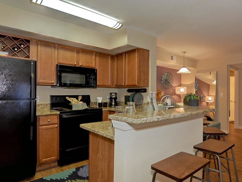 The kitchen has modern appliances and a breakfast bar in each apartment rental.